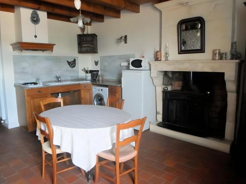 eine Küche mit Tisch und Stühlen und einem Kamin in der Unterkunft La Longère de la Combe - Suzanne in Sainte-Même