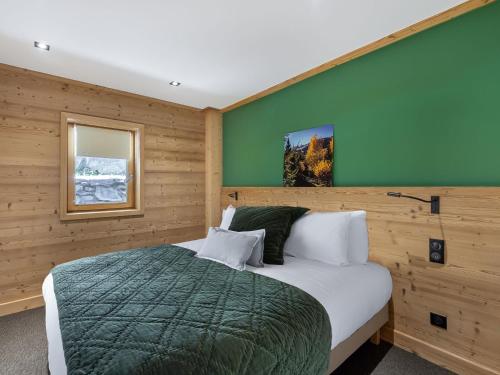 a bedroom with a bed and a green wall at Appartement familial calme 8 pers, près des pistes - FR-1-565-51 in Les Allues