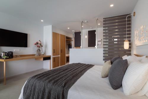a bedroom with a large bed and a television at St John Suites - Adults Only Zakynthos in Tsilivi