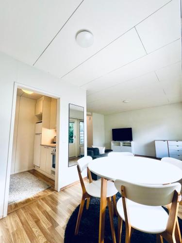 uma sala de estar com uma mesa e cadeiras brancas em Spacious two-room apartment with sauna em Varkaus