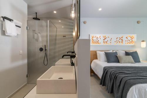 a bedroom with a shower and a bed and a sink at Hotel St.John Suites Adults Only in Tsilivi