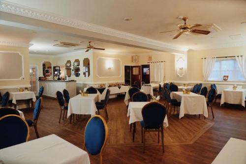 a restaurant with white tables and chairs and a ceiling at The Waverley Hotel in Crewe
