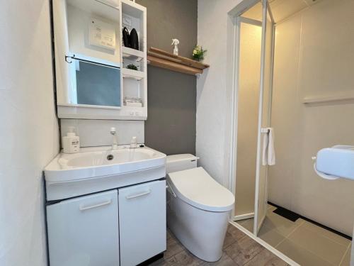Un baño blanco con inodoro y lavabo. en Quan Sea Vista Retreat Japanese Room サウナ付き宿, en Onna