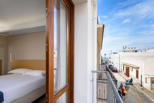 a bedroom with a bed and a balcony with a view at Hotel Calliope in San Vito lo Capo