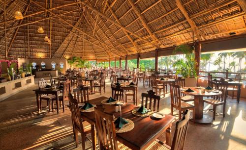 a restaurant with tables and chairs and a large ceiling at Diamonds Mapenzi Beach in Kiwengwa