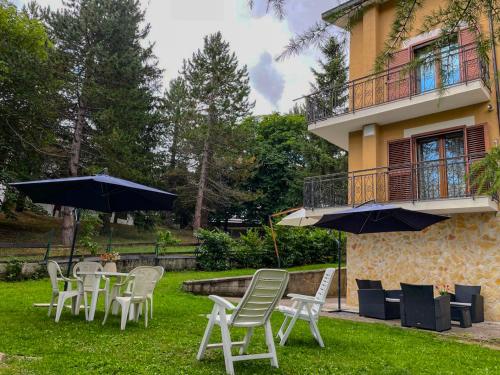 Casa Vacanze - Villa Stefania في بيسكوكوستانزو: مجموعة من الكراسي والمظلات أمام المبنى