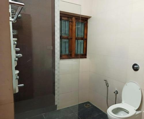 ein Badezimmer mit Toilette und Fenster in der Unterkunft Thistle Cosy Villa in Kozhikode