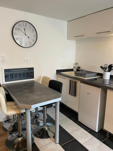 a kitchen with a table and a clock on the wall at T2 Cosy avec jardin et parking gratuit à Troyes in Troyes