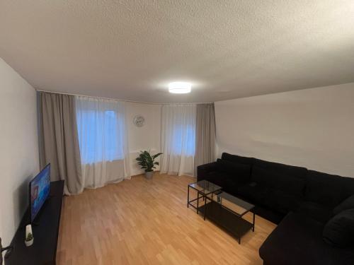a living room with a black couch and a tv at Apartment Airport Dortmund in Holzwickede