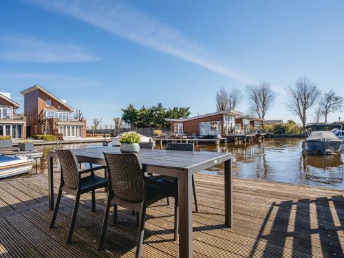 einen Tisch und Stühle auf einer Anlegestelle mit einem Boot in der Unterkunft Holiday Home Busch en Dam by Interhome in Uitgeest