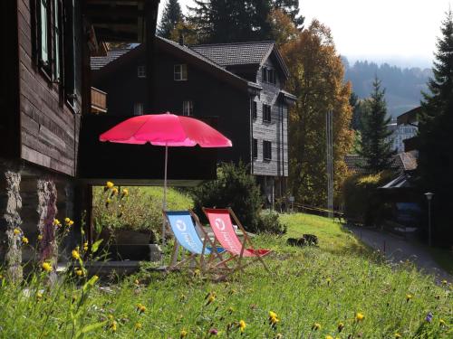 two chairs and a red umbrella in a yard at Studio Helene Studio Christel by Interhome in Wengen