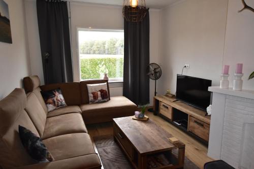 a living room with a couch and a tv at The Holidayhouse - 5 min Efteling - max 5 pers & 1 baby in Loon op Zand