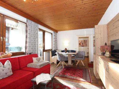 a living room with a red couch and a table at Apartment Tyrol-1 by Interhome in Aschau