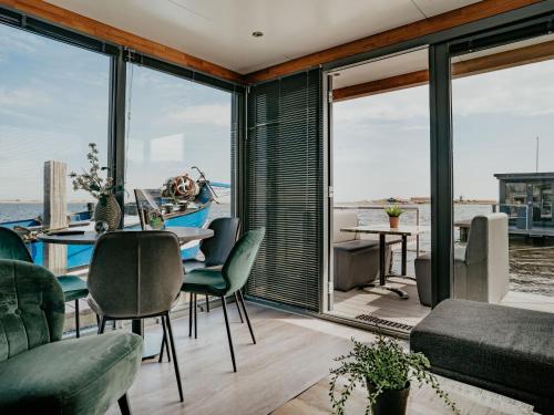 une salle à manger avec une table, des chaises et des fenêtres dans l'établissement Holiday Home De Meerparel-1 by Interhome, à Uitgeest