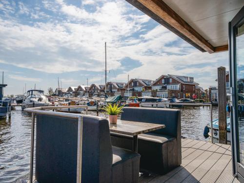 a table and chairs on a dock with boats in the water at Holiday Home De Meerparel-1 by Interhome in Uitgeest
