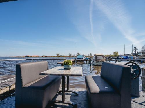 a table and chairs on a dock with a boat at Holiday Home Havenlodge by Interhome in Uitgeest
