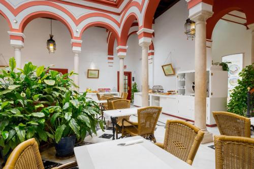 un restaurante vacío con mesas, sillas y plantas en Sercotel Las Casas de los Mercaderes, en Sevilla