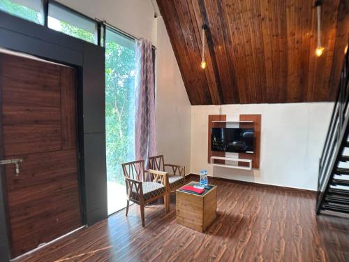 sala de estar con puerta, mesa y sillas en A1 Tiger Resort, en Kolāra