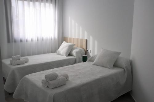 two beds in a white room with towels on them at La Herrada Home in Los Montesinos