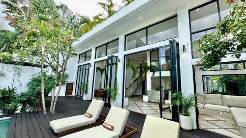 an exterior view of a house with chairs and a pool at Villa Daya Canggu - 5 Mins to Beach, Rooftop Cinema and Private Cook in Canggu