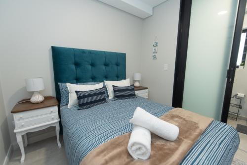 a bedroom with a large blue bed with towels on it at Serenity Suite Bellamare in Summerstrand