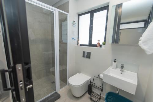 a bathroom with a toilet and a sink and a shower at Serenity Suite Bellamare in Summerstrand