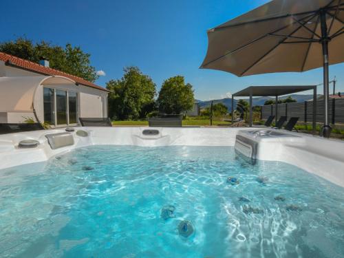 a hot tub with an umbrella in a backyard at Holiday Home Ana by Interhome in Donji Proložac