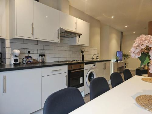 a kitchen with white cabinets and a table and chairs at Spacious 3-Bedroom Apartment with Private Parking & Wi-Fi in Hull