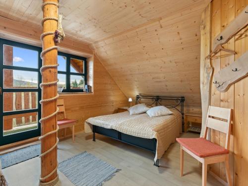 a bedroom in a log cabin with a bed and a chair at Chalet Srub Pohodář by Interhome in Benešov nad Černou