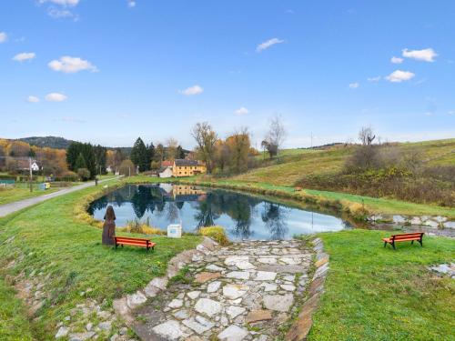 two benches sitting on the grass next to a river at Chalet Quiet place Cabin by Interhome in Benešov nad Černou