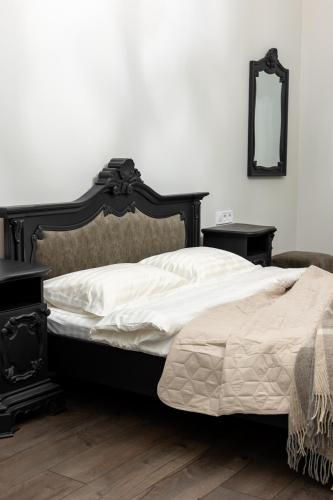 a bedroom with a bed and two tables and a mirror at Romari apartment Братів Рогатинців 32 in Lviv
