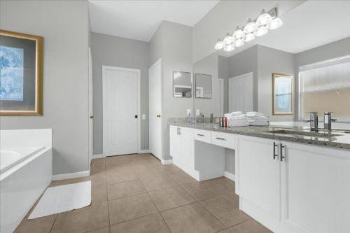 uma cozinha branca com armários brancos e um lavatório em 5 Bedrooms 35 Bathrooms Windsor Palms 8017 Kp em Orlando