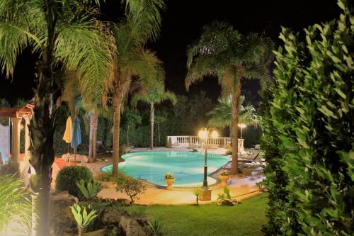 a swimming pool at night with palm trees at Modica Blu Oceano in Modica