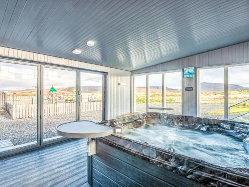 eine Whirlpool-Badewanne in einem Zimmer mit Fenstern in der Unterkunft Holiday Home Benderloch House & Frobost Lodge by Interhome in Daliburgh