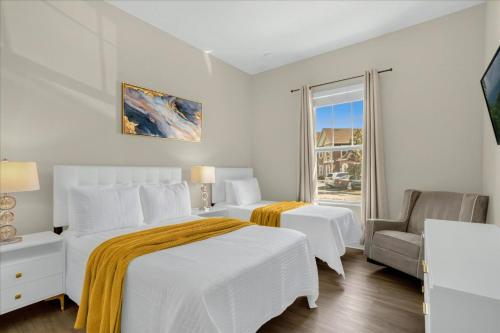 a white bedroom with two beds and a chair at 4 Bedrooms 3 Bathrooms Summerville 2612 Ss in Orlando