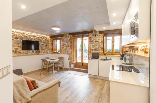 a kitchen and living room with a stone wall at El patio, apartamento en casco histórico con vistas a la iglesia in Castro-Urdiales
