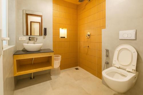 un bagno con lavandino, WC e specchio di Kafal Pako Resort - Luxury Mountain View Stay in Mukteshwar a Mukteshwar