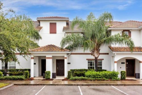 a white house with palm trees in a parking lot at 4 Bedrooms 3 Bathrooms Storey Lake 3195 Pp in Orlando