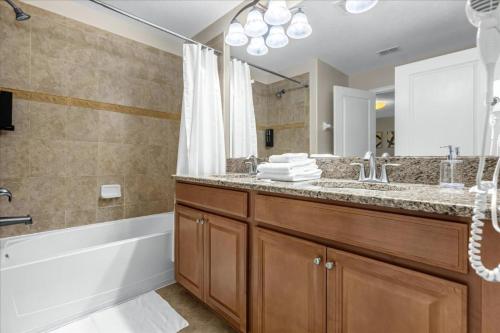 a bathroom with a tub and a sink and a mirror at 4 Bedrooms 3 Bathrooms Storey Lake 3195 Pp in Orlando
