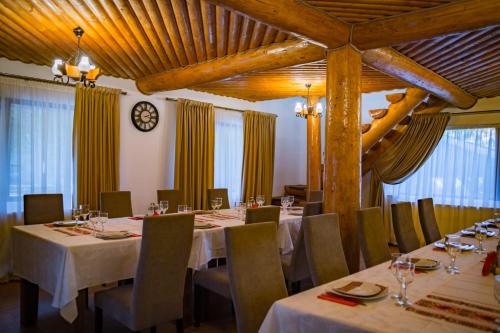 Pensiunea Rustic House Rucăr - Argeș في روكار: غرفة طعام مع طاولات وكراسي وساعة