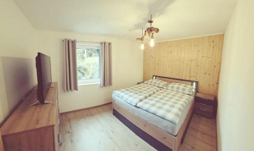 兰格尔斯道夫Konis Ferienwohnung的一间卧室，里面有一张床和一台平板电视