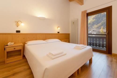 una camera da letto con un letto bianco e una finestra di Hotel Bleis a Ponte di Legno