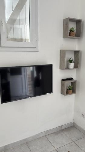 Un televisor de pantalla plana en una pared blanca en Résidence Flores De Maria, en Le Marin