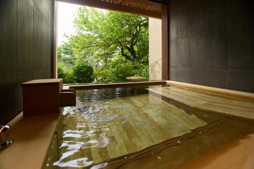 a pool of water in a bathroom with a window at Jinya Ryokan in Hadano