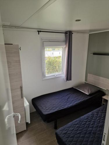 a small bedroom with a bed and a window at TRIGANO Savina 2022 in Litteau