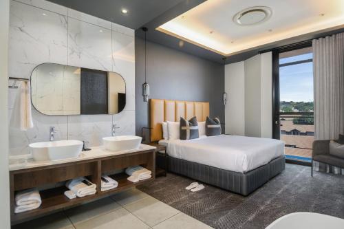 a bedroom with a bed and a sink and a mirror at The Capital Boardwalk in Gqeberha