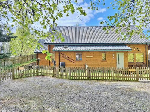 une maison en bois avec une clôture devant elle dans l'établissement Baltinna East - by Where Stags Roar, à Newtonmore