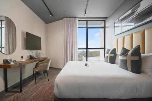 a bedroom with a bed and a desk and a window at The Capital Boardwalk in Gqeberha
