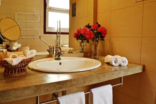 ein Badezimmer mit einem Waschbecken und einer Vase mit roten Rosen in der Unterkunft Casa Da Fonte in Algarvia