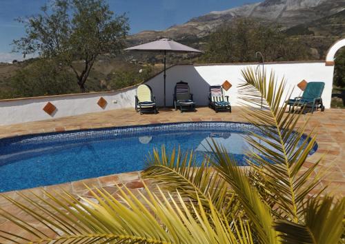 ein Swimmingpool mit Stühlen und einem Sonnenschirm in der Unterkunft Ferienhaus mit Privatpool für 4 Personen ca 190 m in Sedella, Andalusien Costa del Sol in Sedella